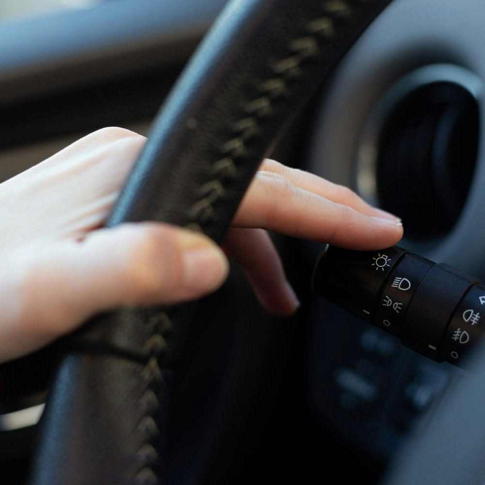 Close-up of a driver's hand on a vehicle turn signal stalk