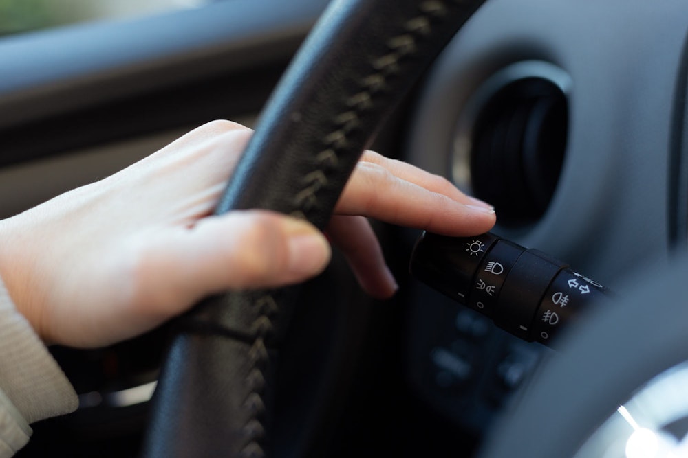 Close-up of a driver's hand on a vehicle turn signal stalk