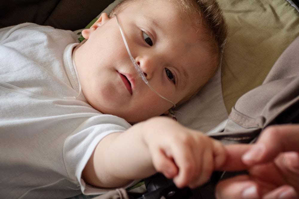 Baby with cerebral palsy reaching for parents' hand