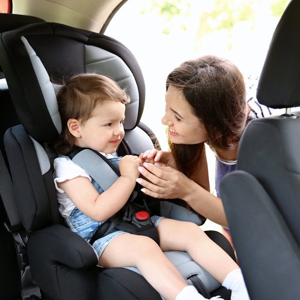 Mother putting child in car seat