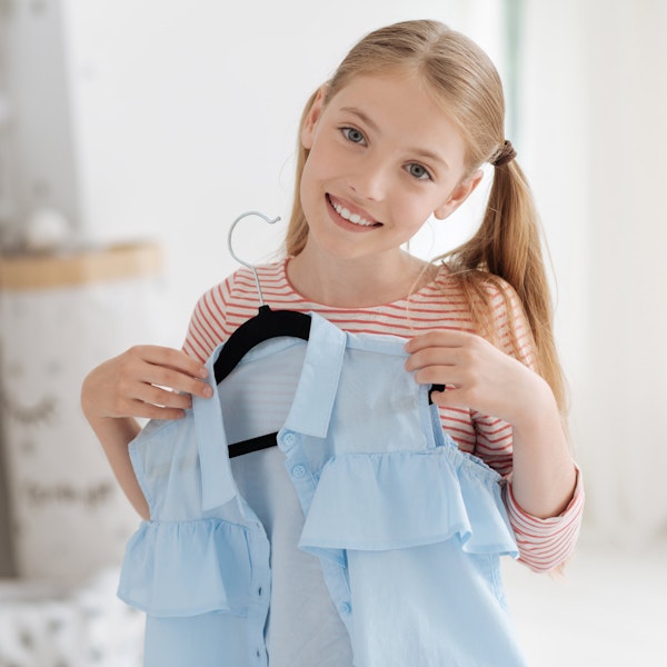 Young girl holding blouse on hanger