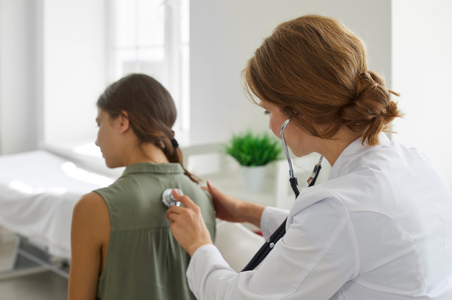 Doctor using stethoscope to listen to young girl's back