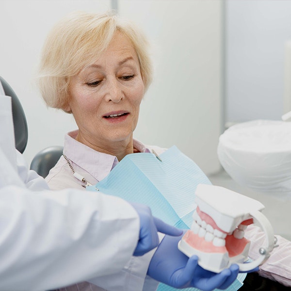 Dentist showing model of dentures to patient