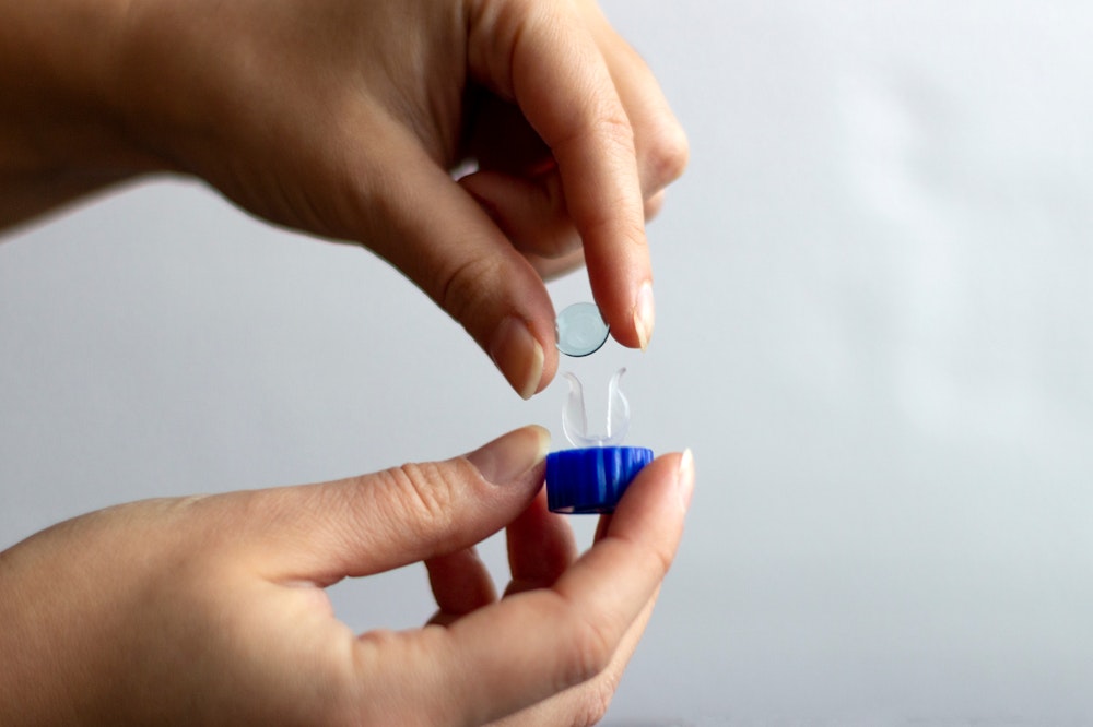 Person putting contact lens in container