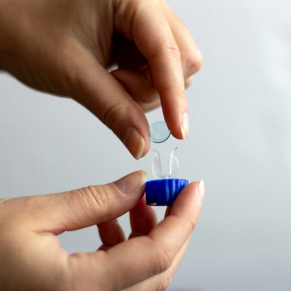 Person putting contact lens in container