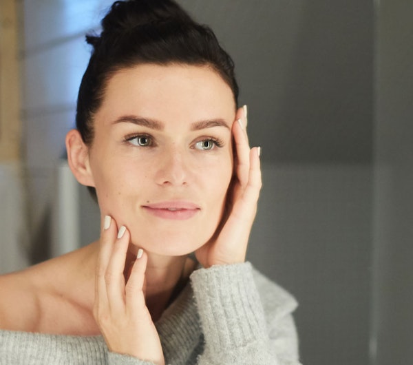 Woman looking at skin in mirror