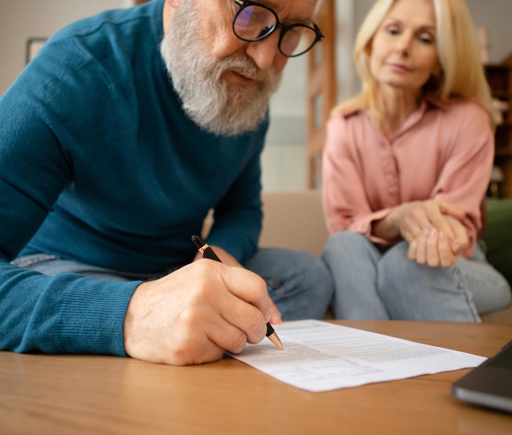 Older man signing will with witness in the back