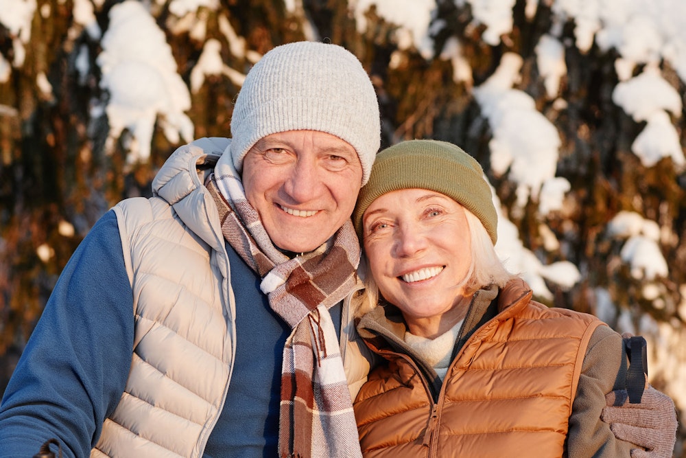 Smiling elderly couple wearing snow gear