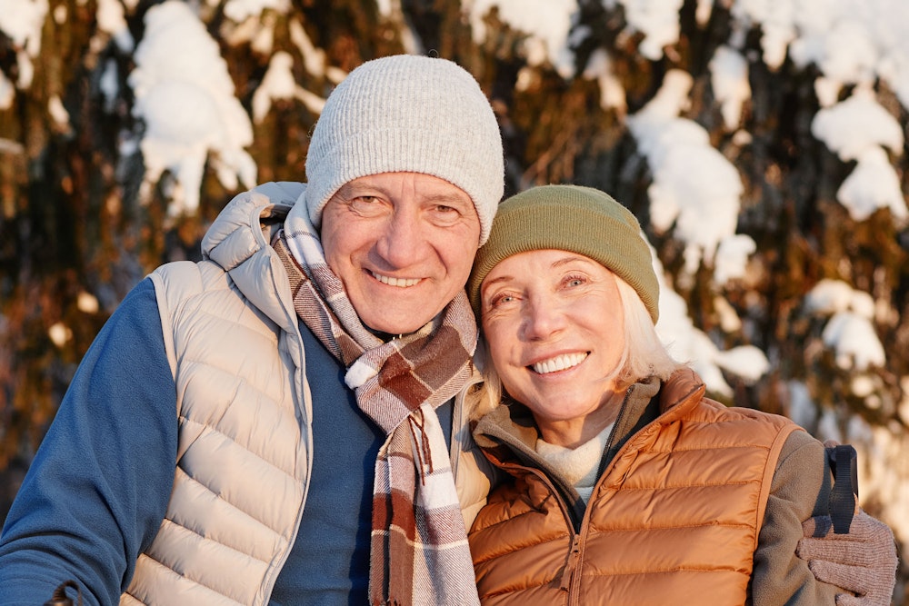 Smiling elderly couple wearing snow gear