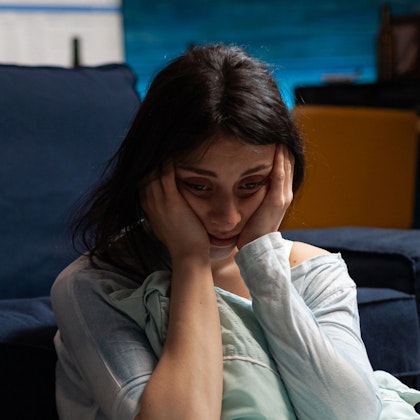 distressed young woman sitting on floor