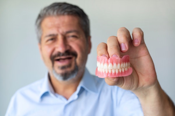 Man holding removable dentures