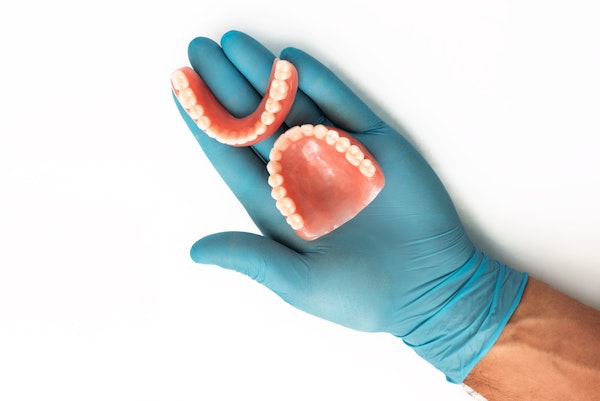 gloved hand holding a denture