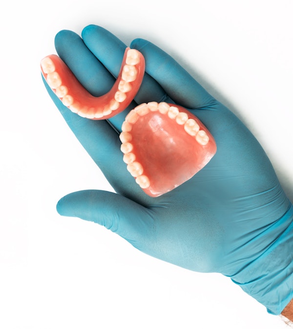 gloved hand holding a denture