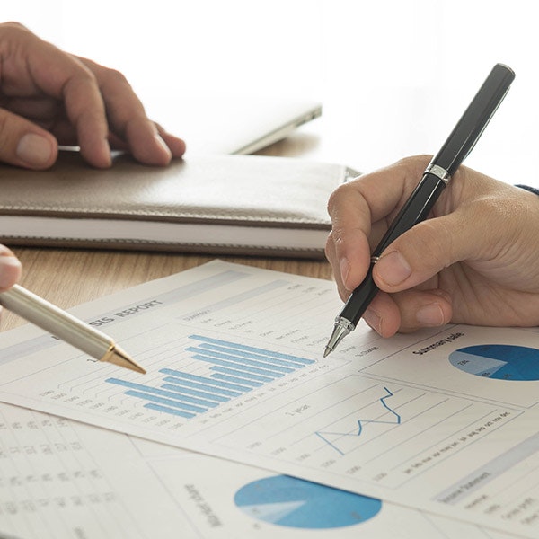 Hands holding pens over paperwork