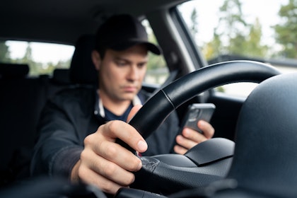 Man in black cap on his phone while driving