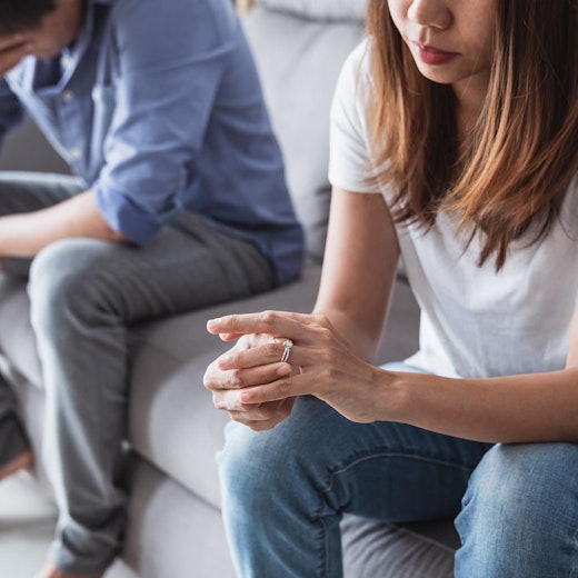 Woman taking ring off, and man sitting behind her