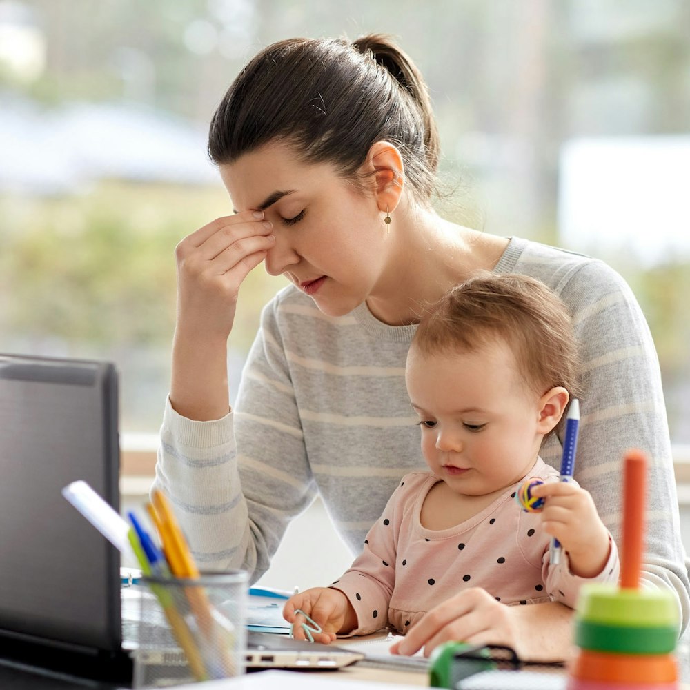 Tired mother looking through financial documents with a baby