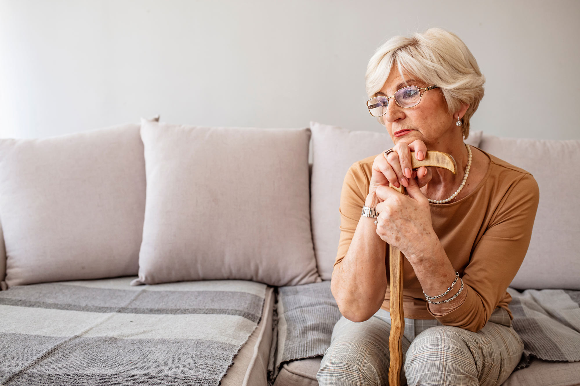 Sad elderly woman gripping cane