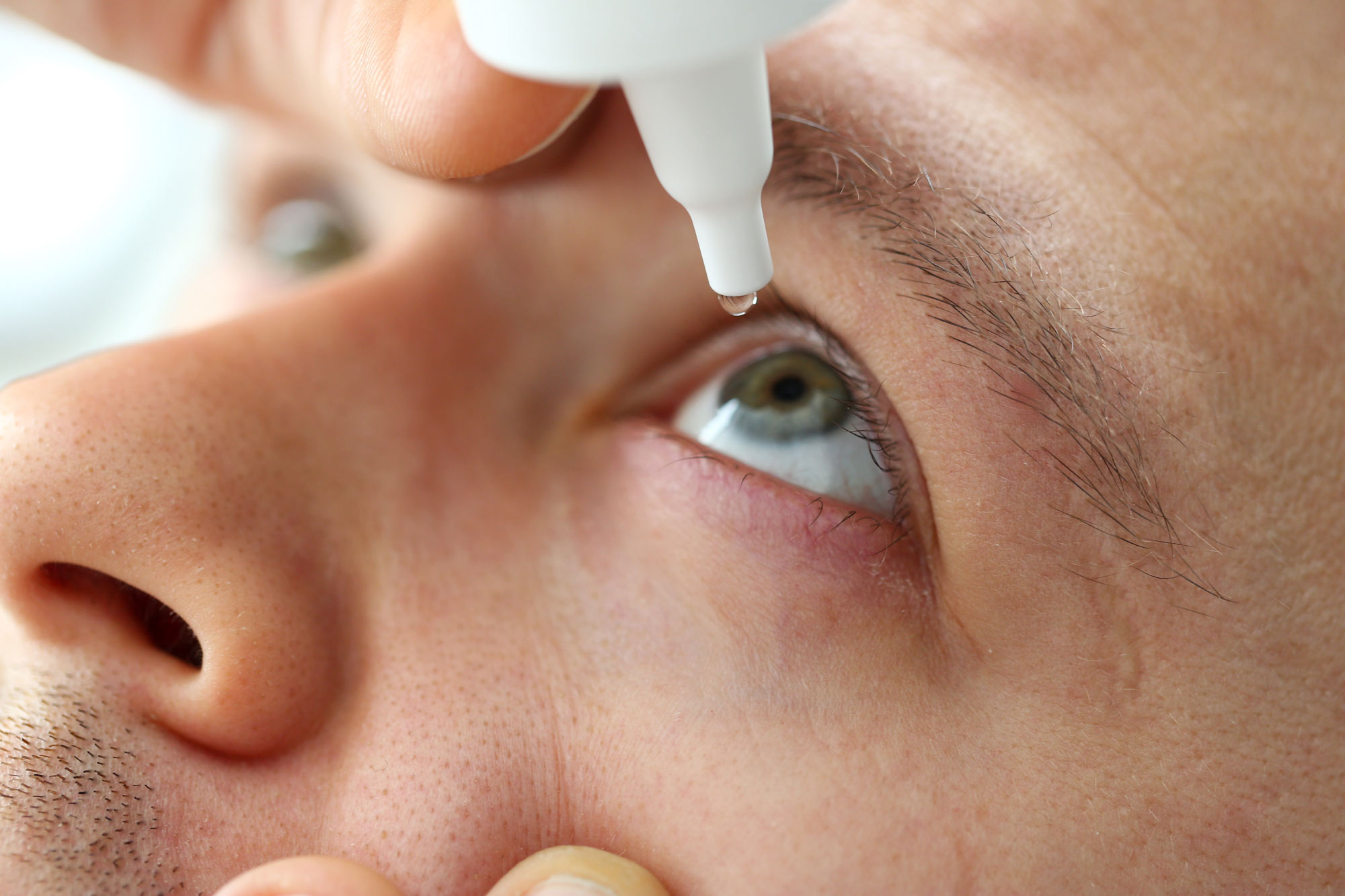Man putting in eye drops