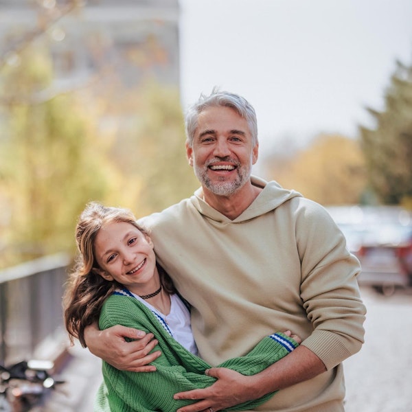Father hugging young daughter outdoors