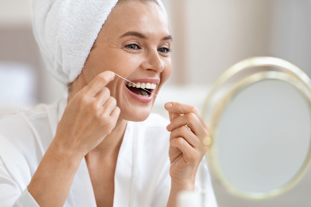 Happy dental implant patient flossing at home