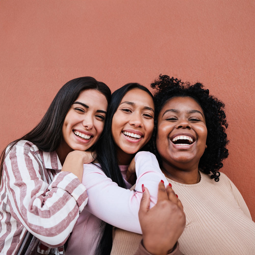 Three friends holding each other and smiling