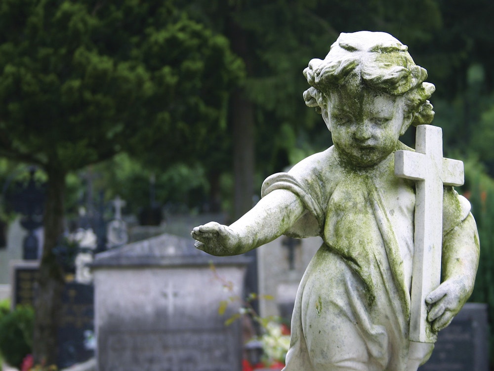 Child statue carrying a cross in a cemetery
