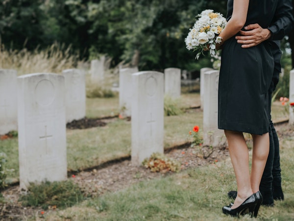 Couple holding flowers in front of tombstones