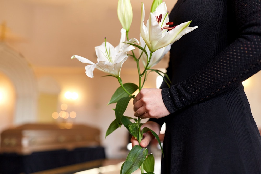Mourning family member holding flowers during funeral