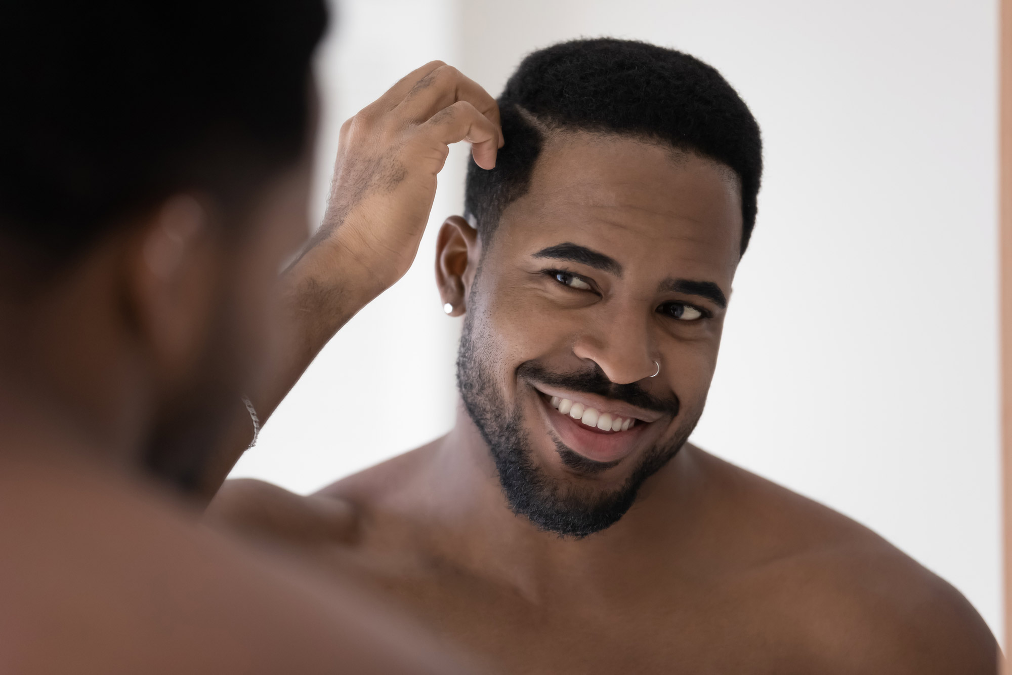 Man smiling while looking at facelift in mirror