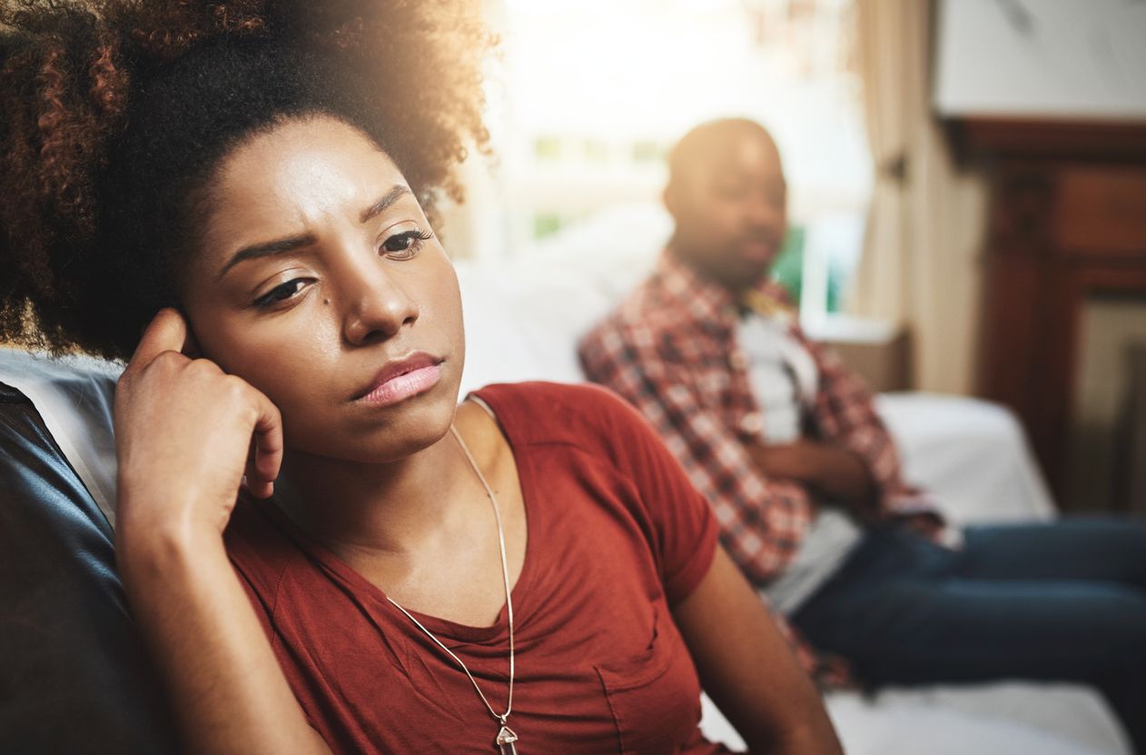 woman with a sad look on her face and a man with his arms folded in the background