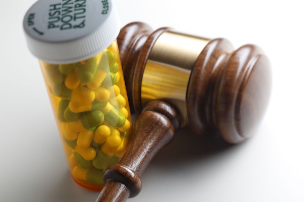 A close-up shot of a prescription bottle and a gavel.