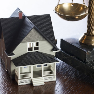 Photo of a miniature house next to legal scales