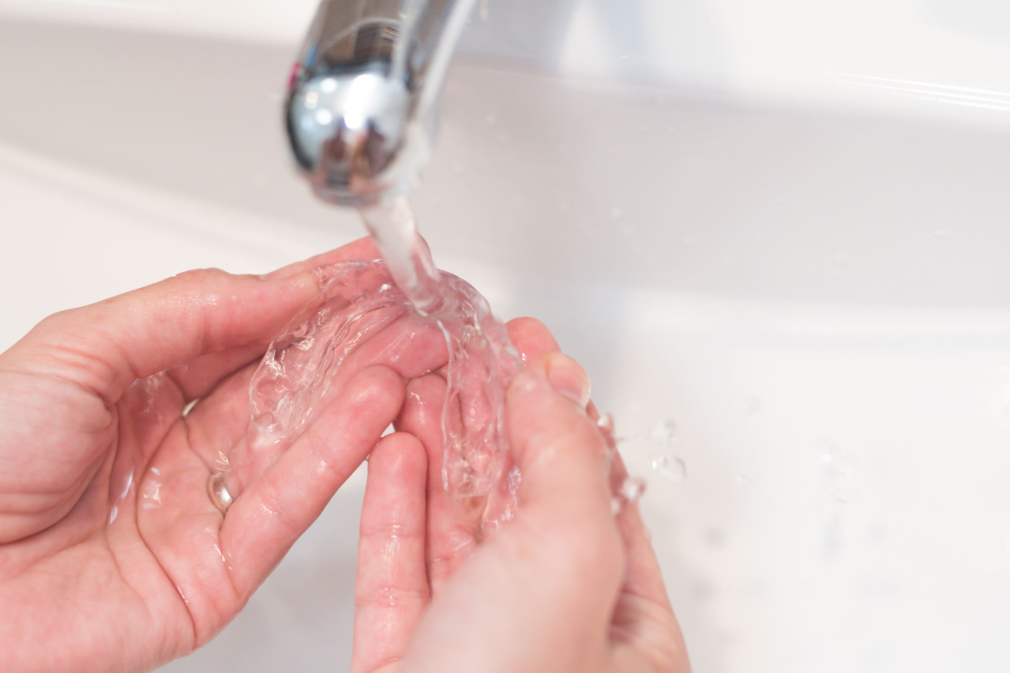 Person washing Invisalign aligner in water
