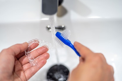 Person cleaning clear aligners