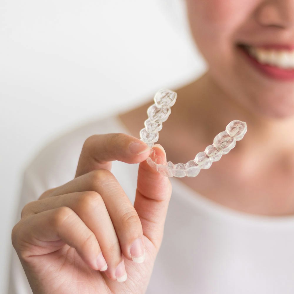 Woman holding Invisalign tray