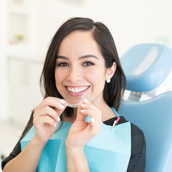 Woman holding invisalign in dental chair
