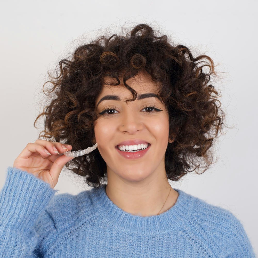 Woman smiling and holding Invisalign