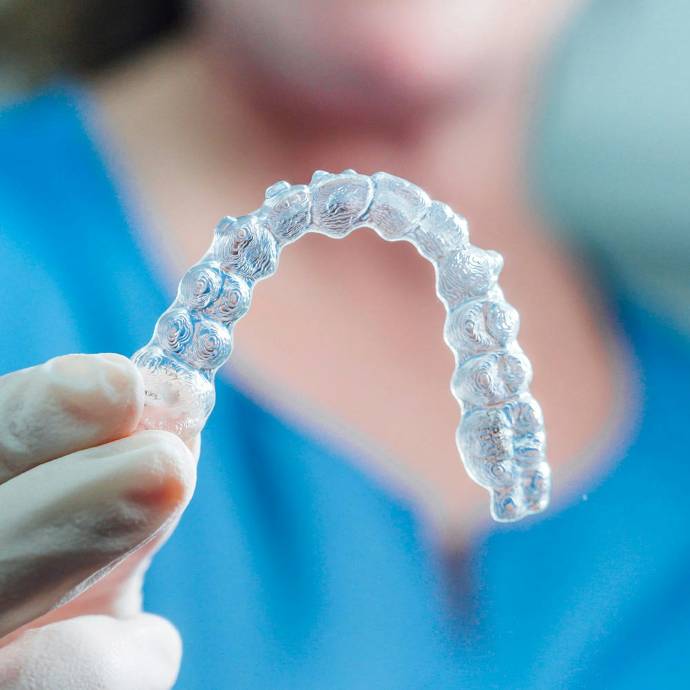 Hand holding up an Invisalign tray