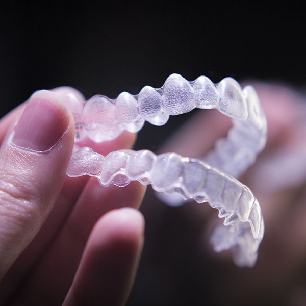 hand holding two Invisalign aligners
