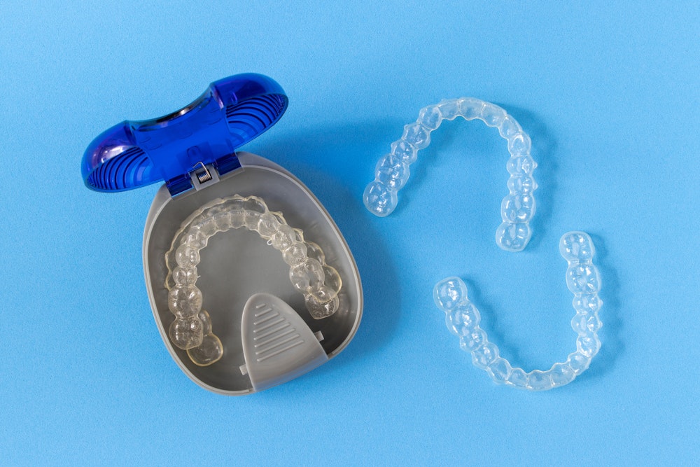 Clear aligner trays in container and on blue background