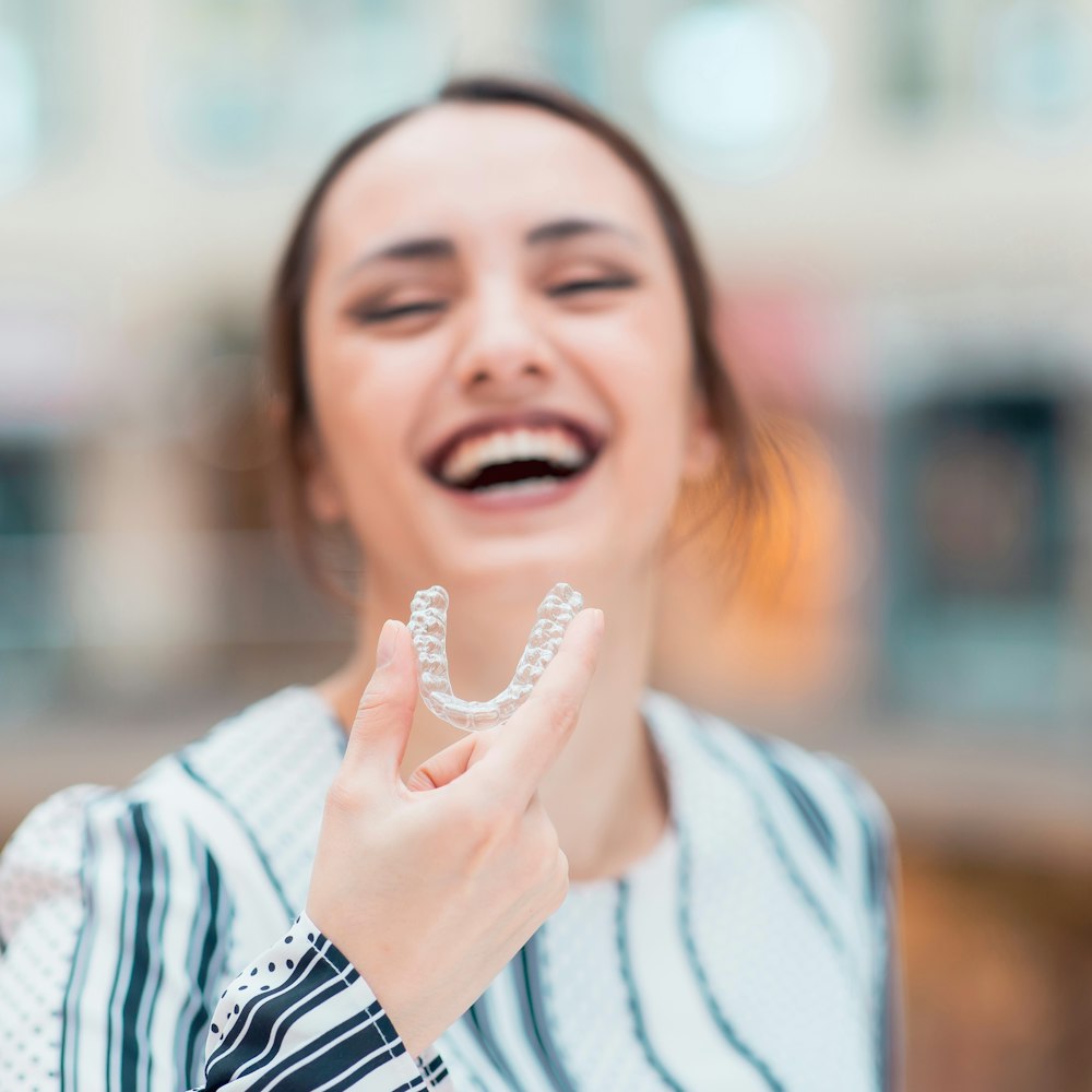 Smiling woman holding Invisalign