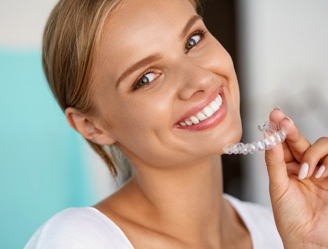 Smiling woman holding Invisalign