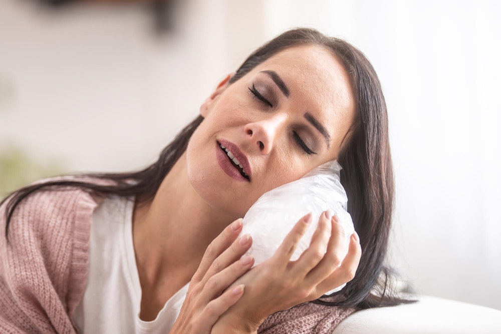 Woman holding ice pack against her cheek