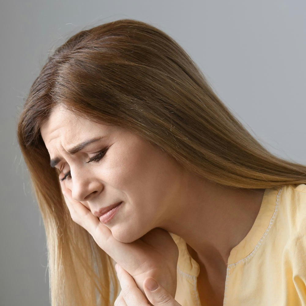 Young dark-haired woman rubbing jaw