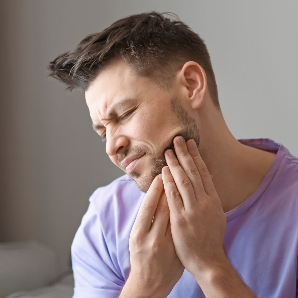 Man holding jaw in discomfort