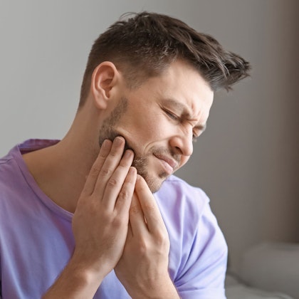 Man clutching teeth in pain