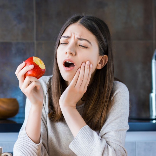 Young girl with jaw pain eating fruit