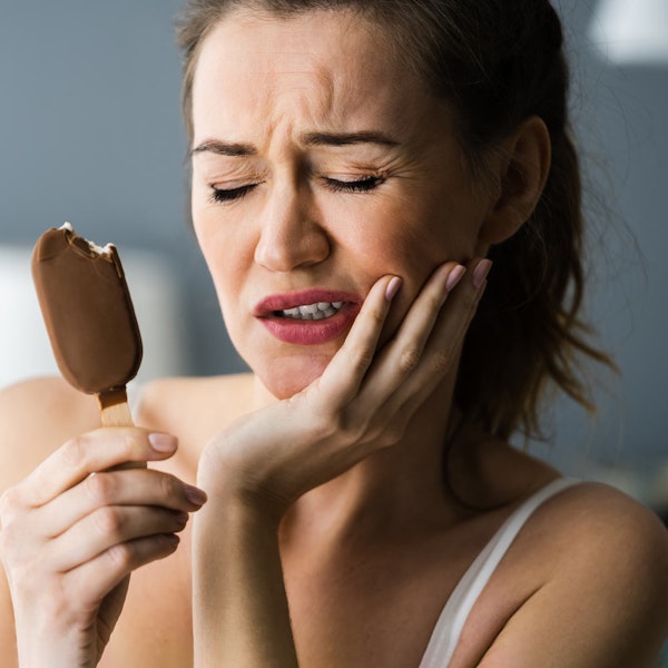 Woman having jaw pain after eating a cold ice cream bar