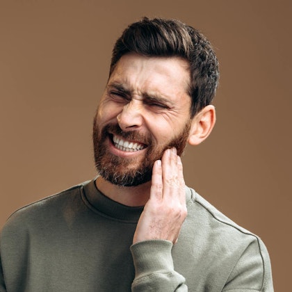 Man holding jaw in pain